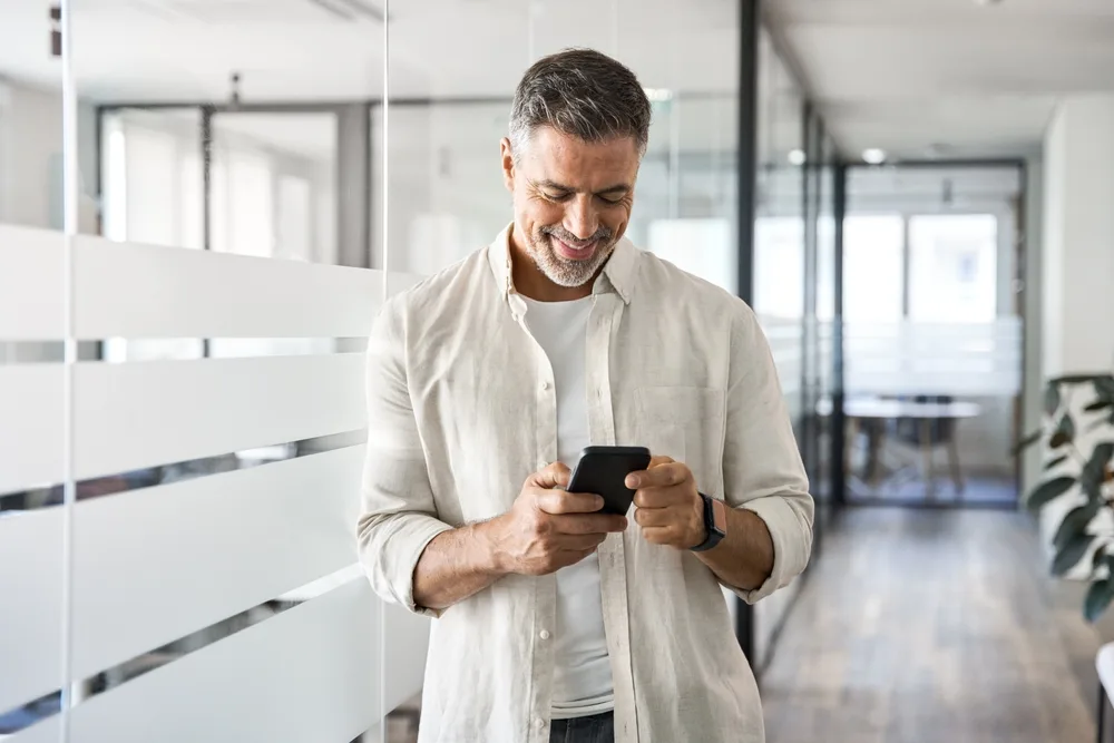 Cum să recunoști și să previi fraudele financiare? Sfaturi și recomandări utile 2 barbat utilizand un smartphone la birou