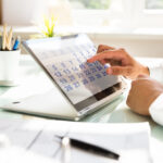 barbat in camasa alba la birou utilizand un calendar pe display touch screen cu data scadenta